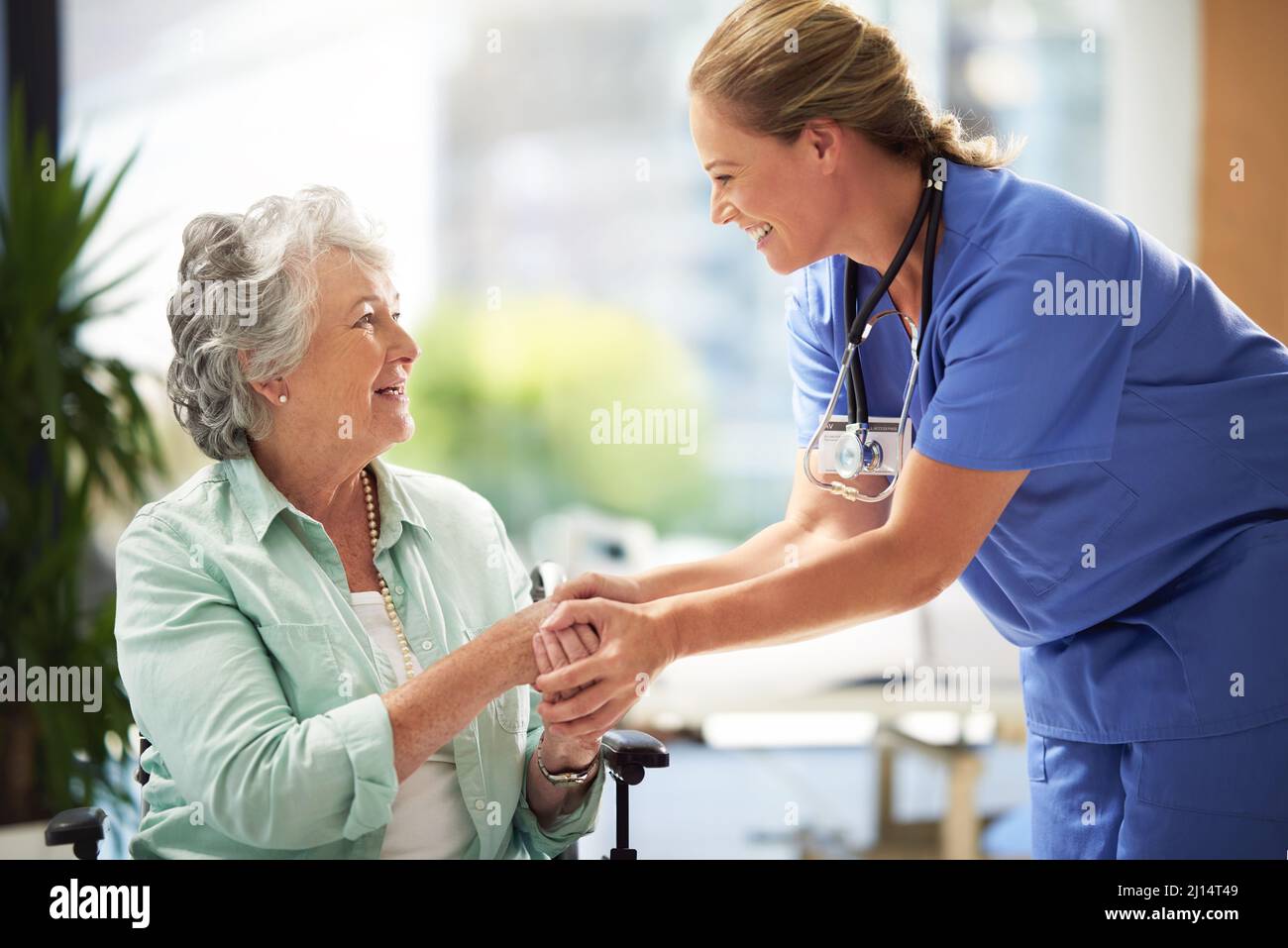 She has a great way with her patiends. Shot of a doctor shaking hands with a smiling senior woman sitting in a wheelchair. Stock Photo