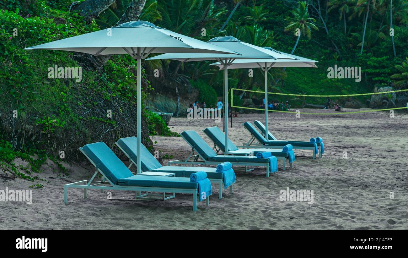 Photo shows Atlantic Ocean beach. Caribbean coastline has yellow sand. Loungers for relaxation and sunbathing are visible. In addition to sun loungers Stock Photo