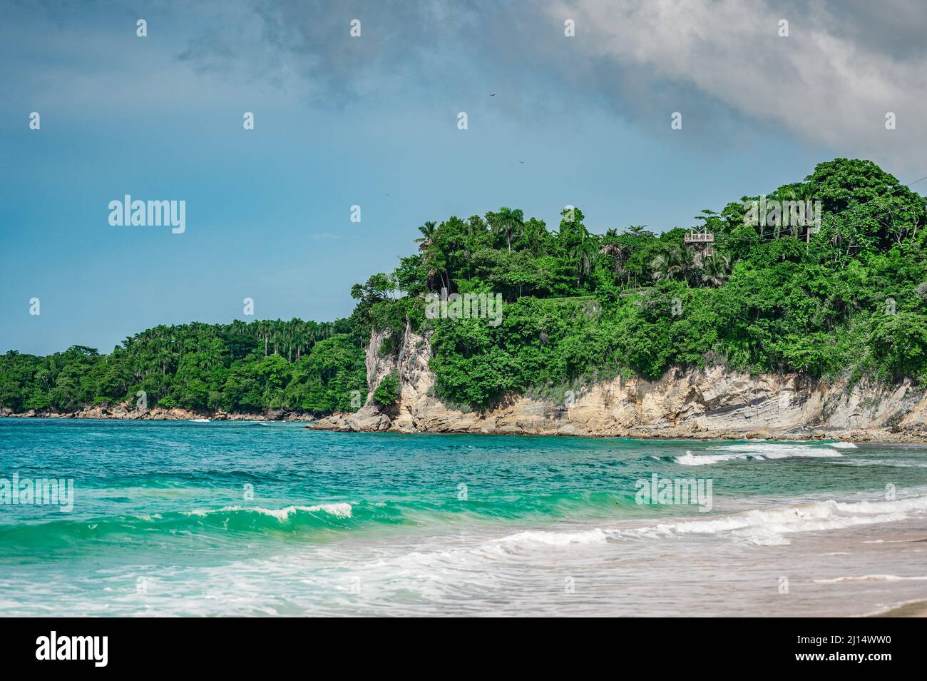 Photo of a sandy beach in the foreground from the Dominican Republic. The picture clearly shows the magnificent sand from the Atlantic Ocean and the b Stock Photo
