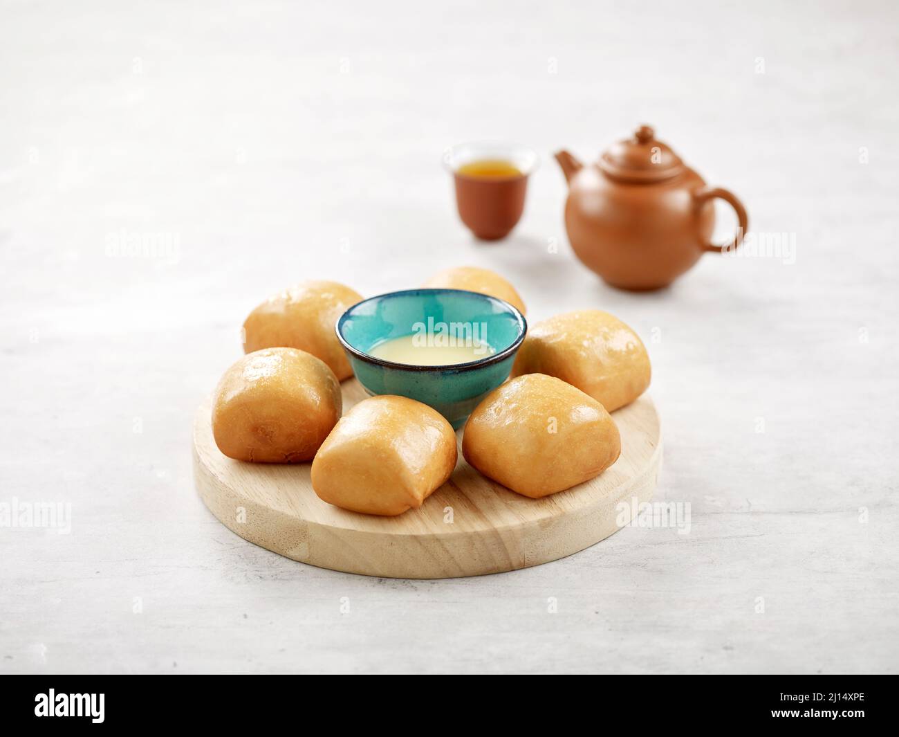 Golden Fried Mantou or Chinese fried bun with condensed milk isolated on wooden board side view on grey background Stock Photo