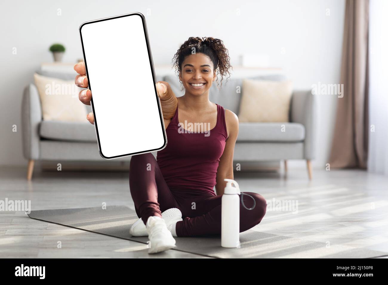 Happy athletic black woman showing mobile phone, mockup Stock Photo