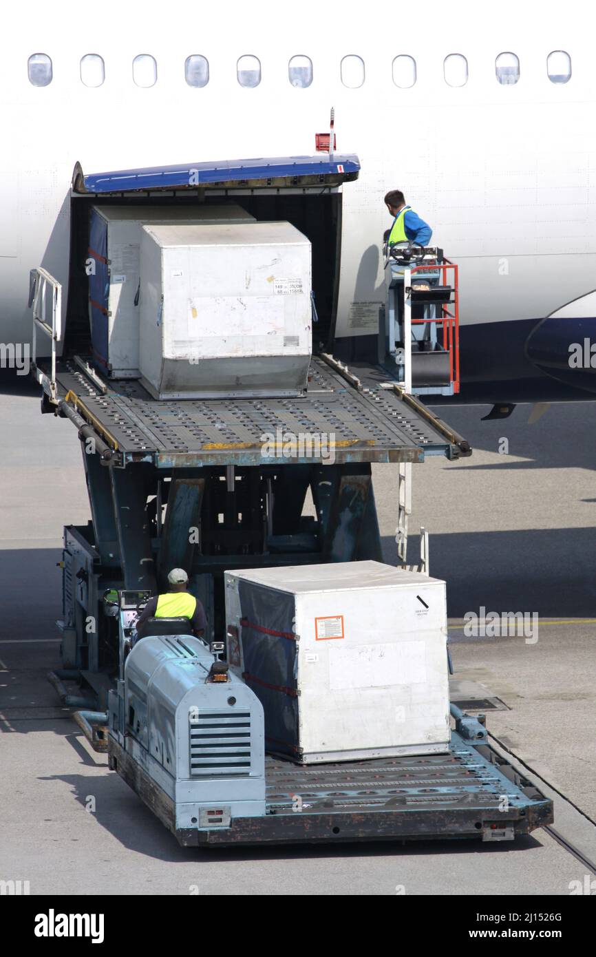 unit load devices being loaded into airliner at international airport Stock Photo