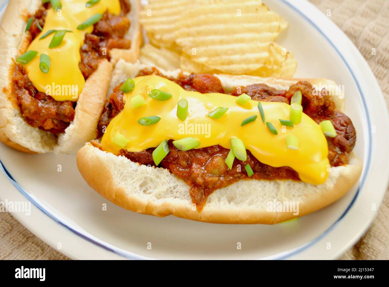 Loaded Chili Dog with Cheddar Cheese and Scallion Served with Wavy Potato Chips Stock Photo
