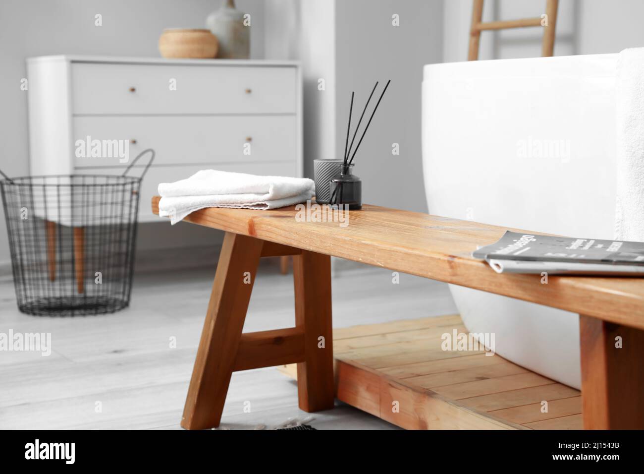 Wooden bench with reed diffuser and towel in bathroom Stock Photo - Alamy