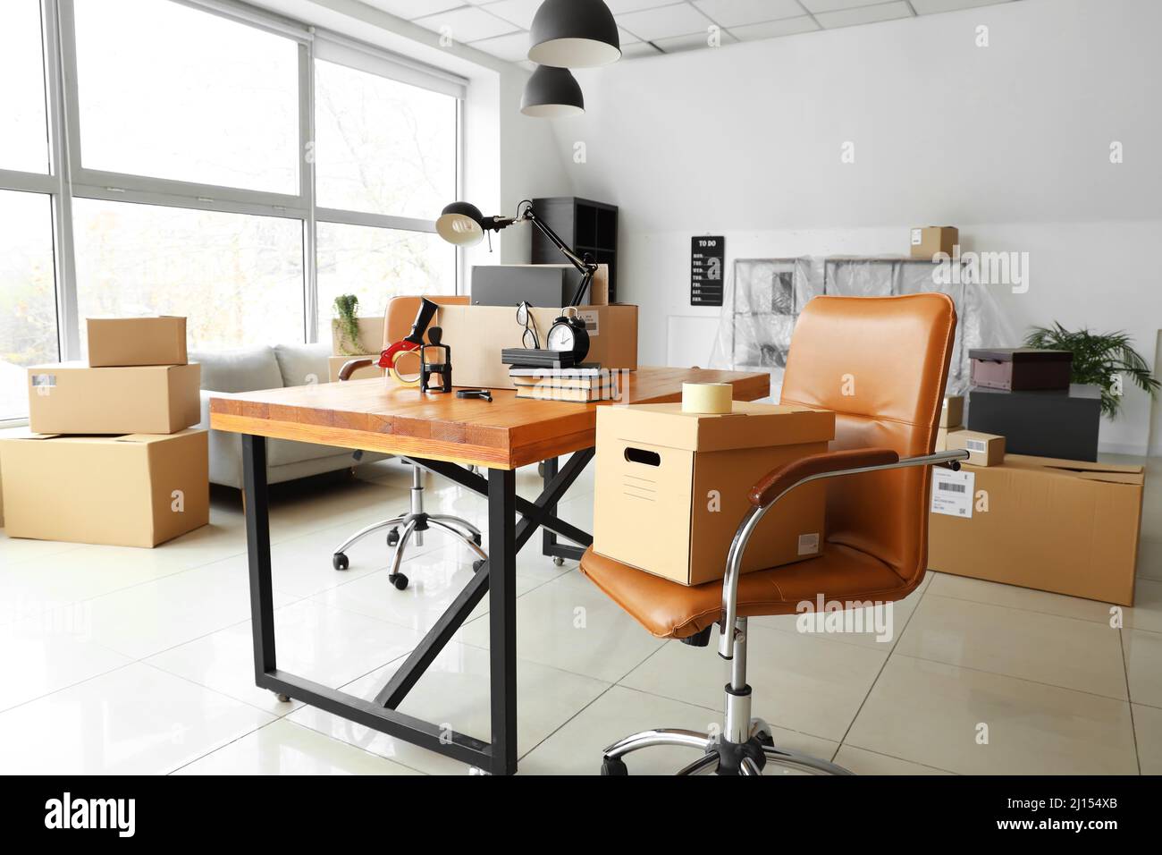 Cardboard boxes with belongings and furniture in interior of office on moving day Stock Photo