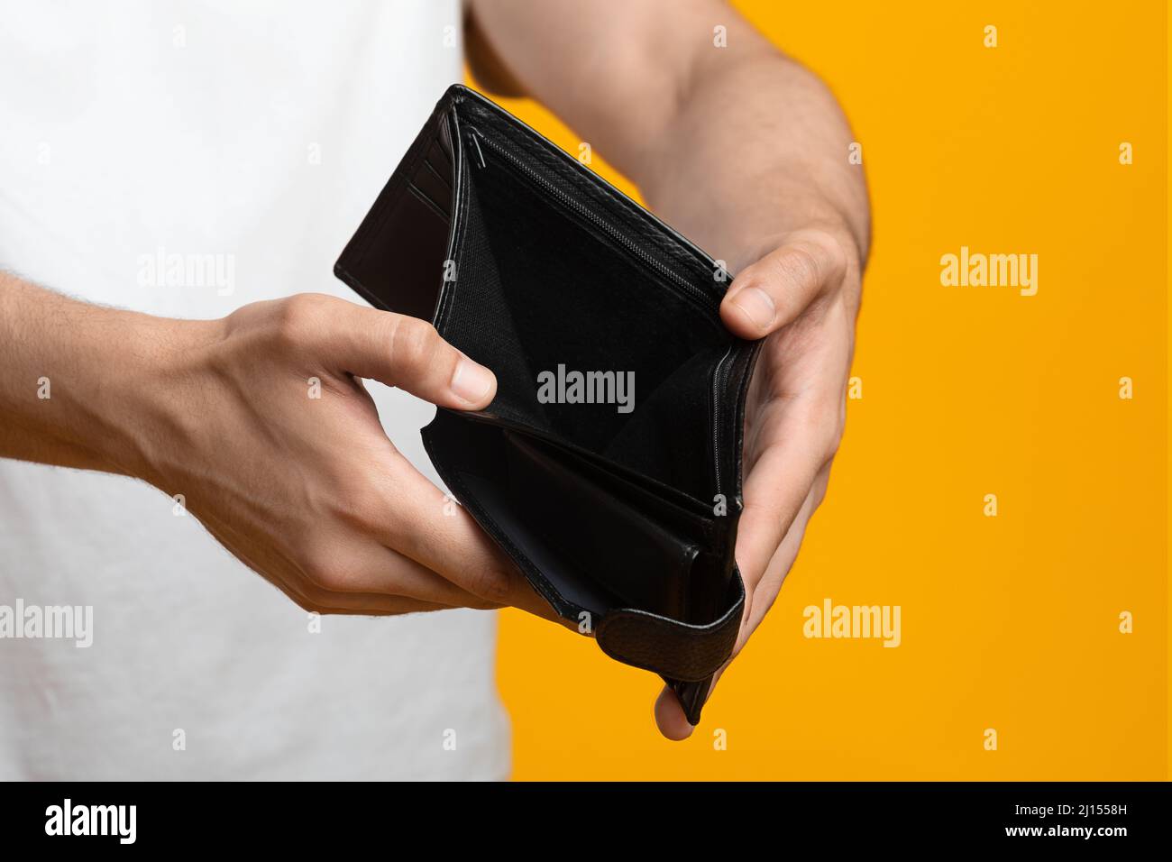 Unrecognizable man showing empty wallet at studio, closeup Stock Photo