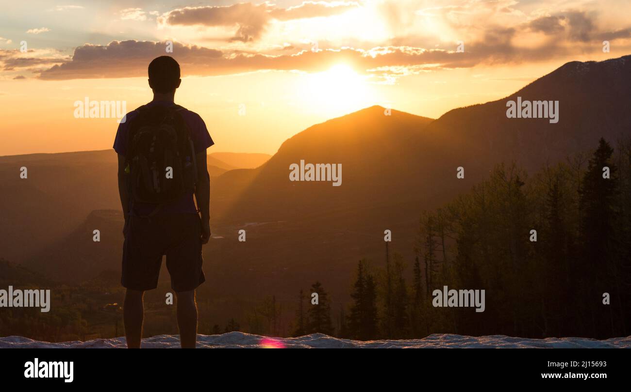 Adventurer stands watching a mountainous sunset in Colorado Stock Photo