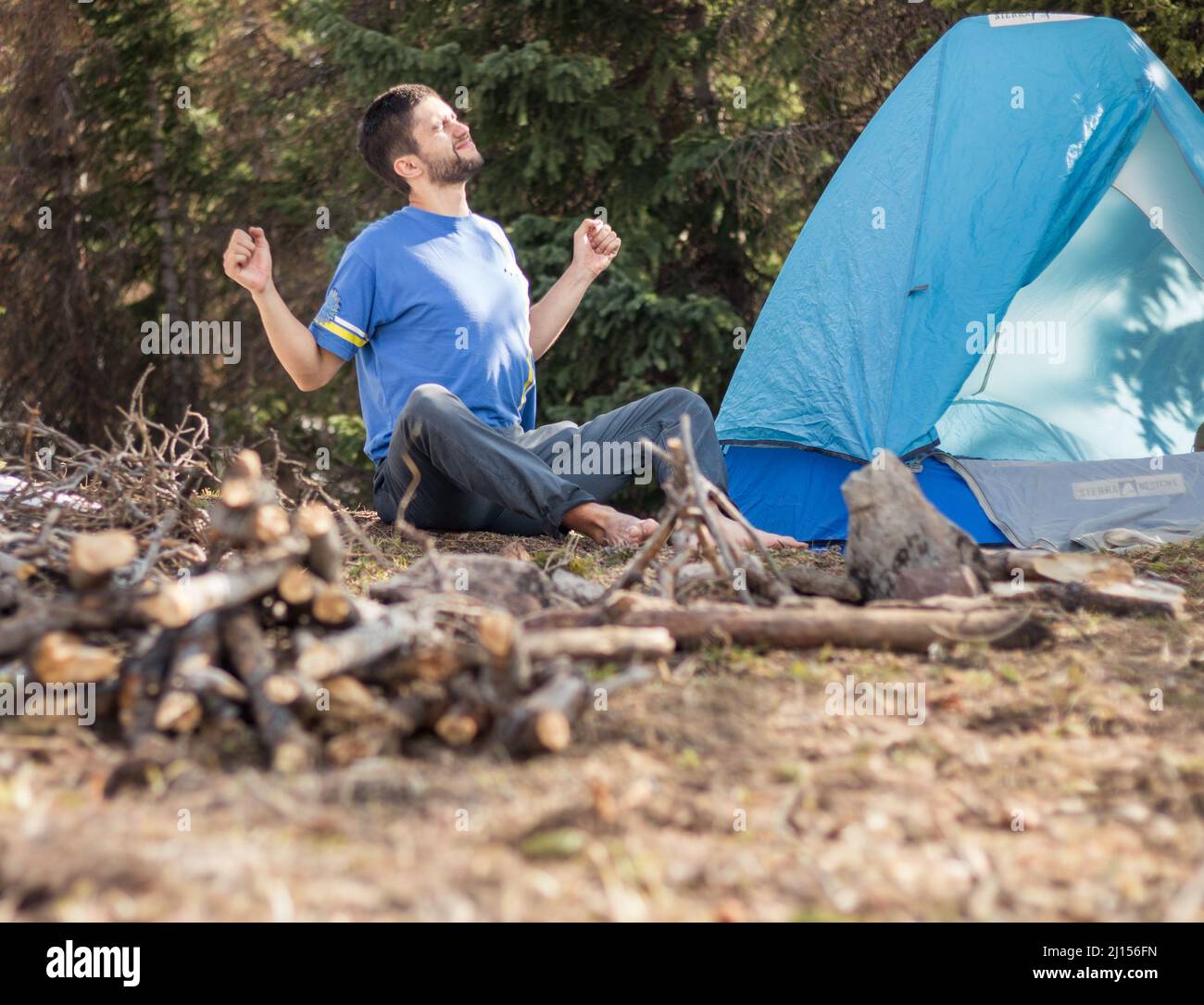 Outdoorsy guy stretching at campsite in the forest Stock Photo