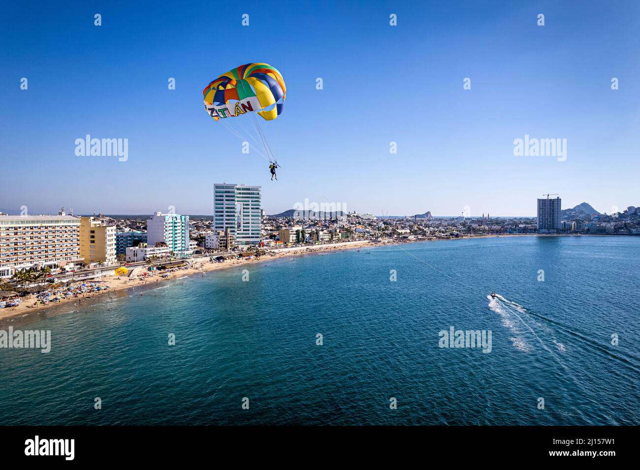 A parasailer glides over the ocean near the beach and malecon of Mazatlan, Sinaloa, Mexico. Stock Photo