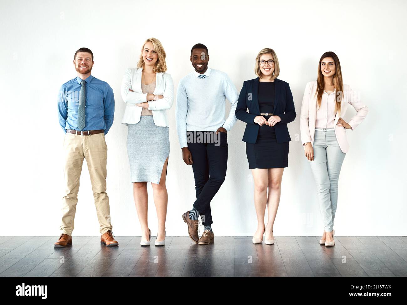 We call the shots. Portrait of a group of work colleagues standing in a line while using their wireless devices against a white background. Stock Photo