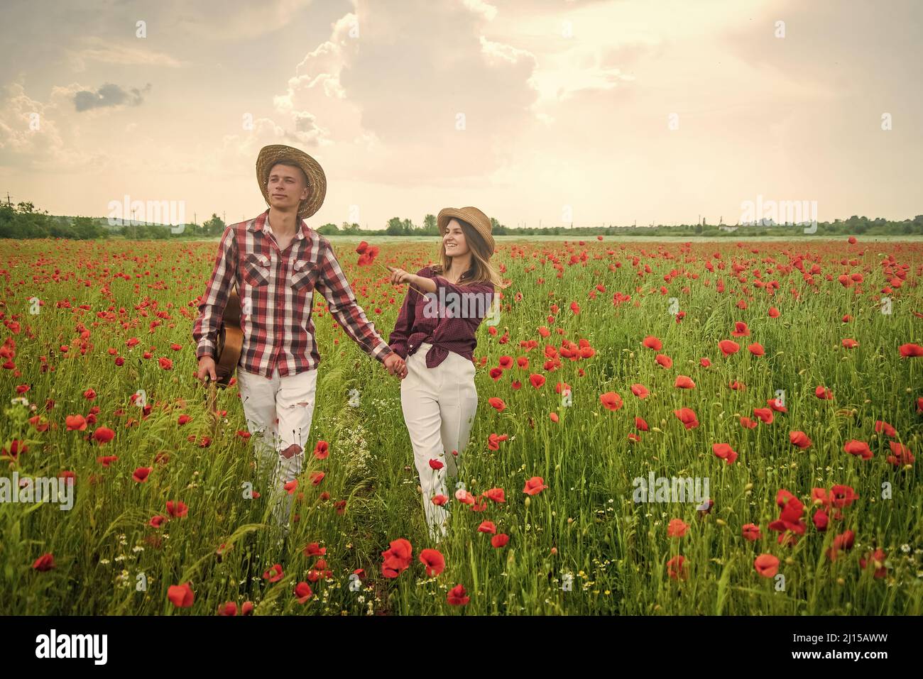 Young couple in a poppy field holding hands, family values Stock Photo ...