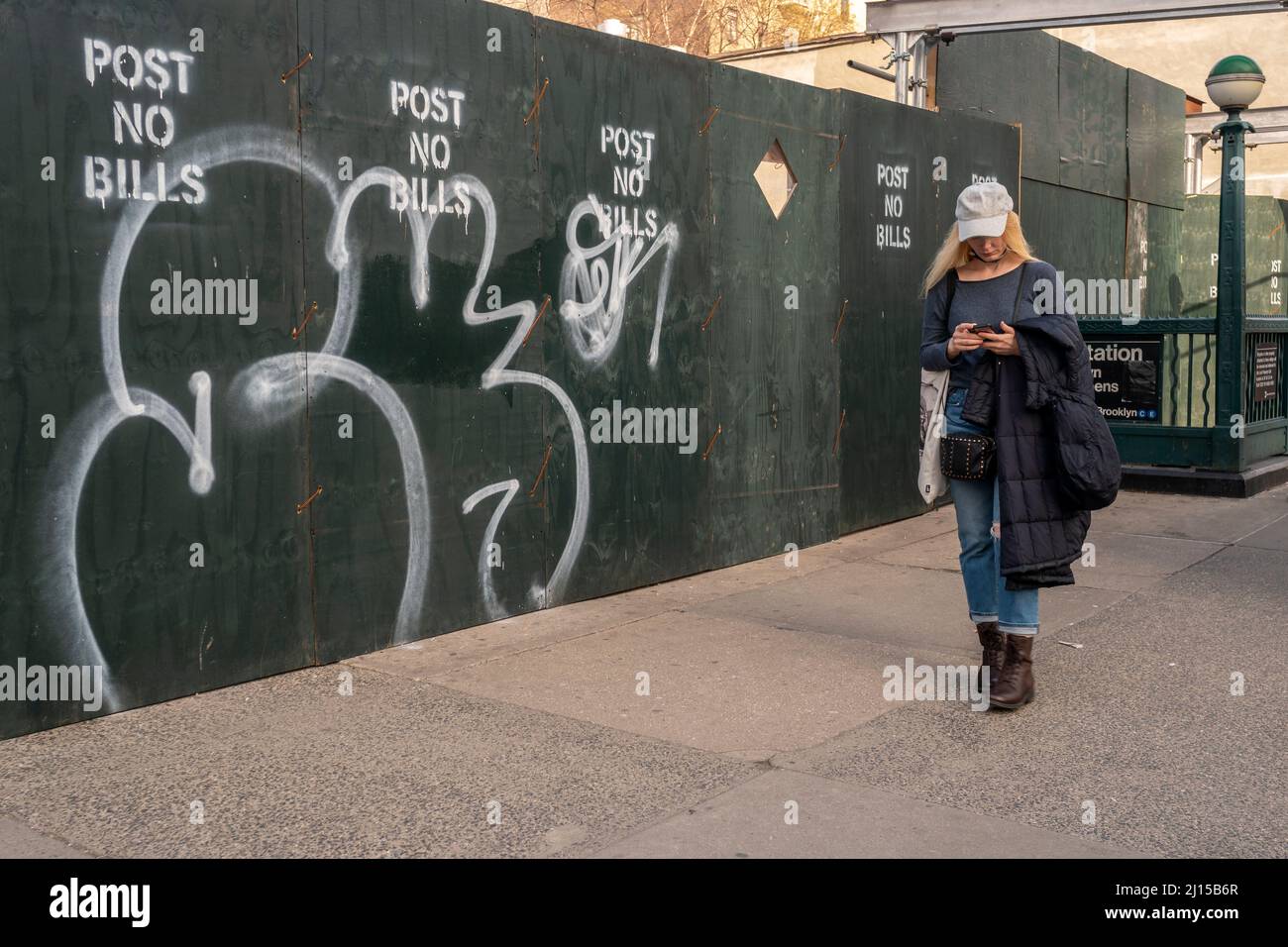 Distracted woman walks past the demolition of the John Q. Aymar Building, a Chelsea landmark in New York on Tuesday, March 15, 2022.  (© Richard B. Levine) Stock Photo