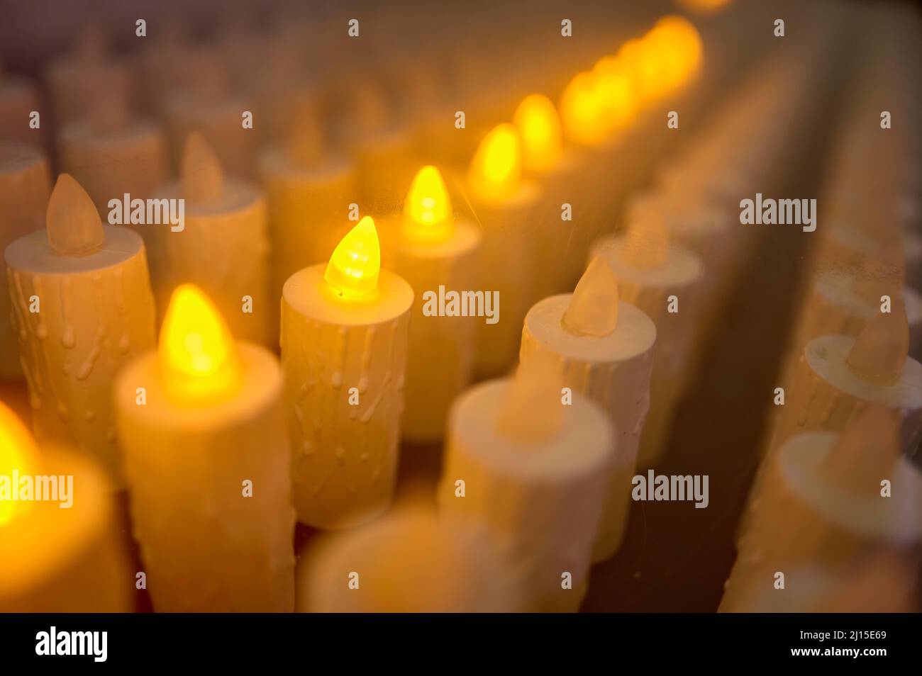detail of an electronic lampstand with some lit candles in a church Stock Photo