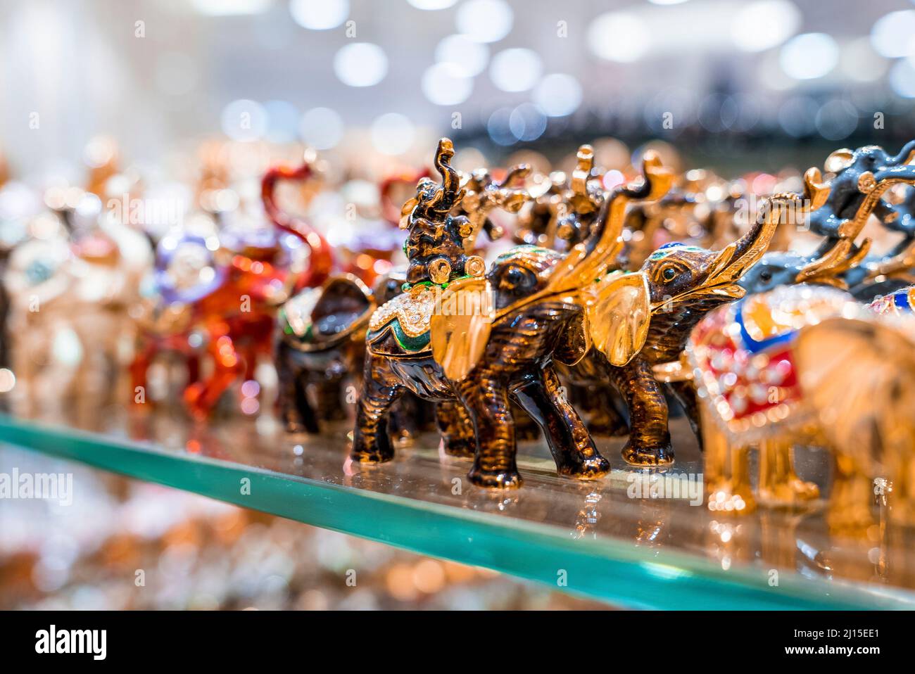 Various colorful elephant figurines display on shelf for sale in shop
