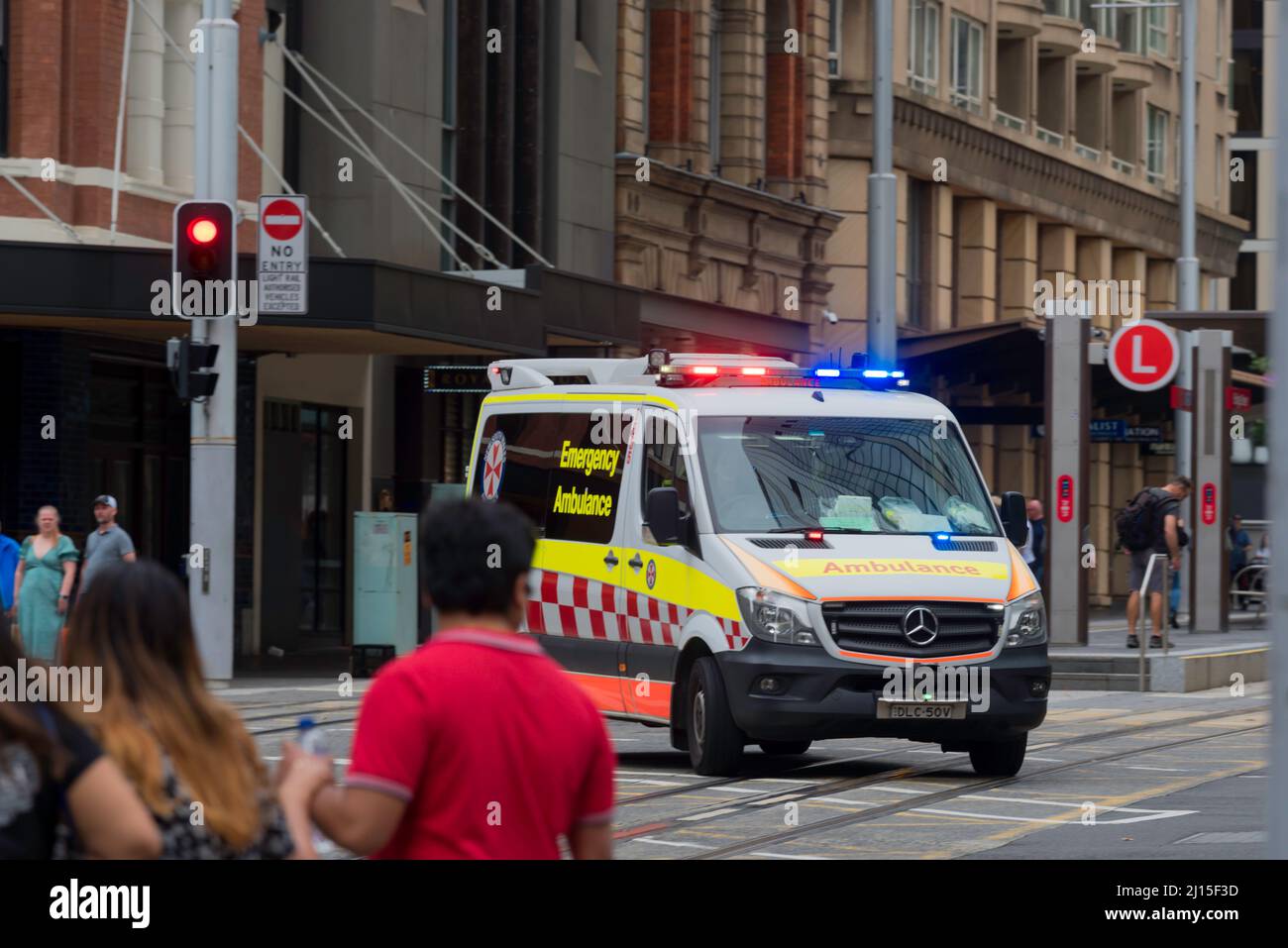 An ambulance with lights flashing turns from Hunter Street onto George Street in the centre of Sydney, Australia on a Saturday Stock Photo