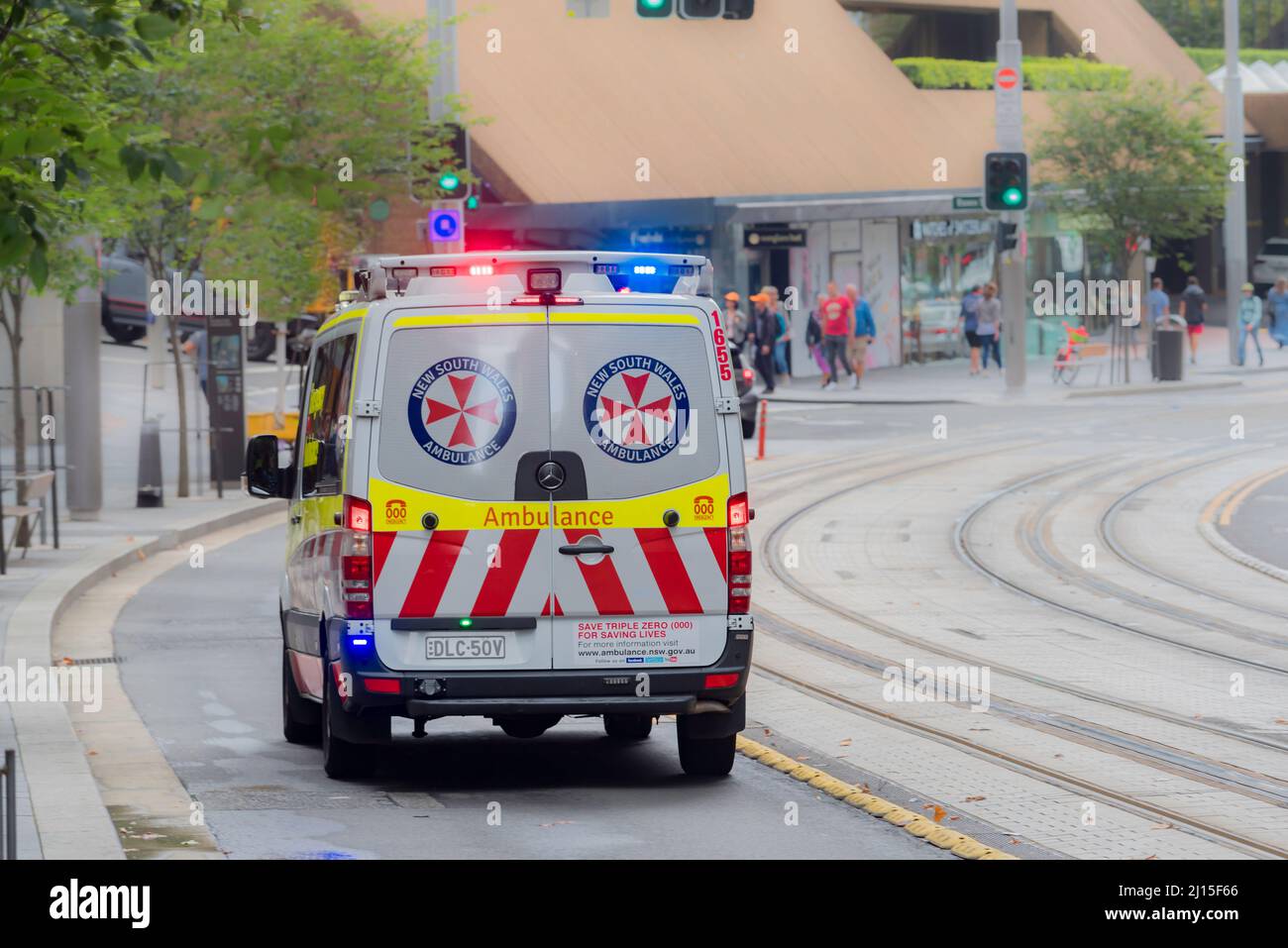 An ambulance with lights flashing moves down George Street in the centre of Sydney, Australia on a Saturday Stock Photo