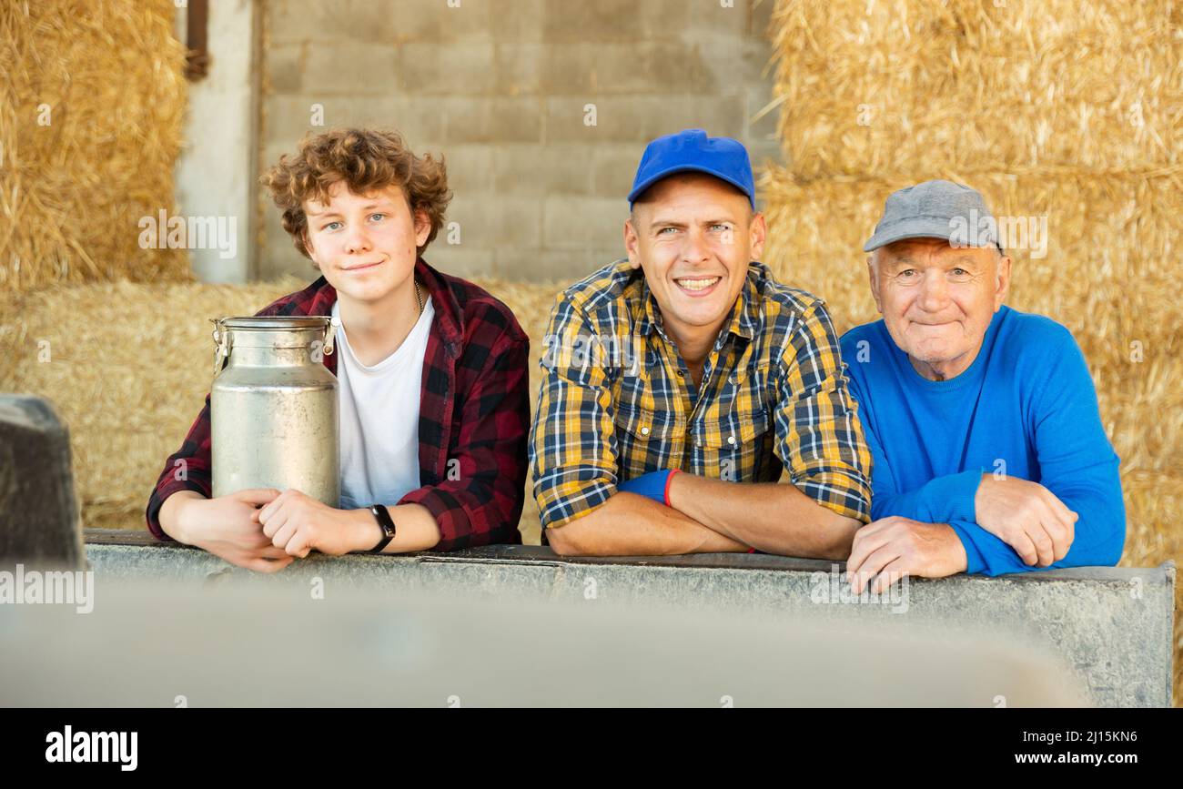 Various aged farmers standing inside hay bales storage Stock Photo