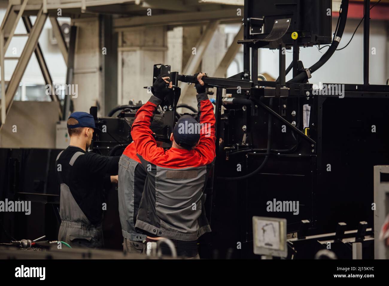 Industrial workers assembles agricultural harvester in workshop. Stock Photo