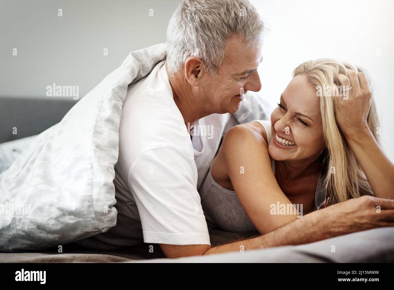 Sleeping in over the weekend is one of lifes great pleasures. Shot of an affectionate couple spending the day in bed. Stock Photo