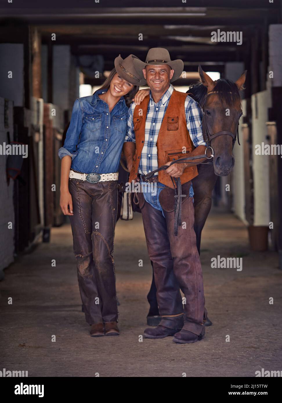 Life at the ranch. Shot of a cowboy and cowgirl leading a horse out of a stable. Stock Photo