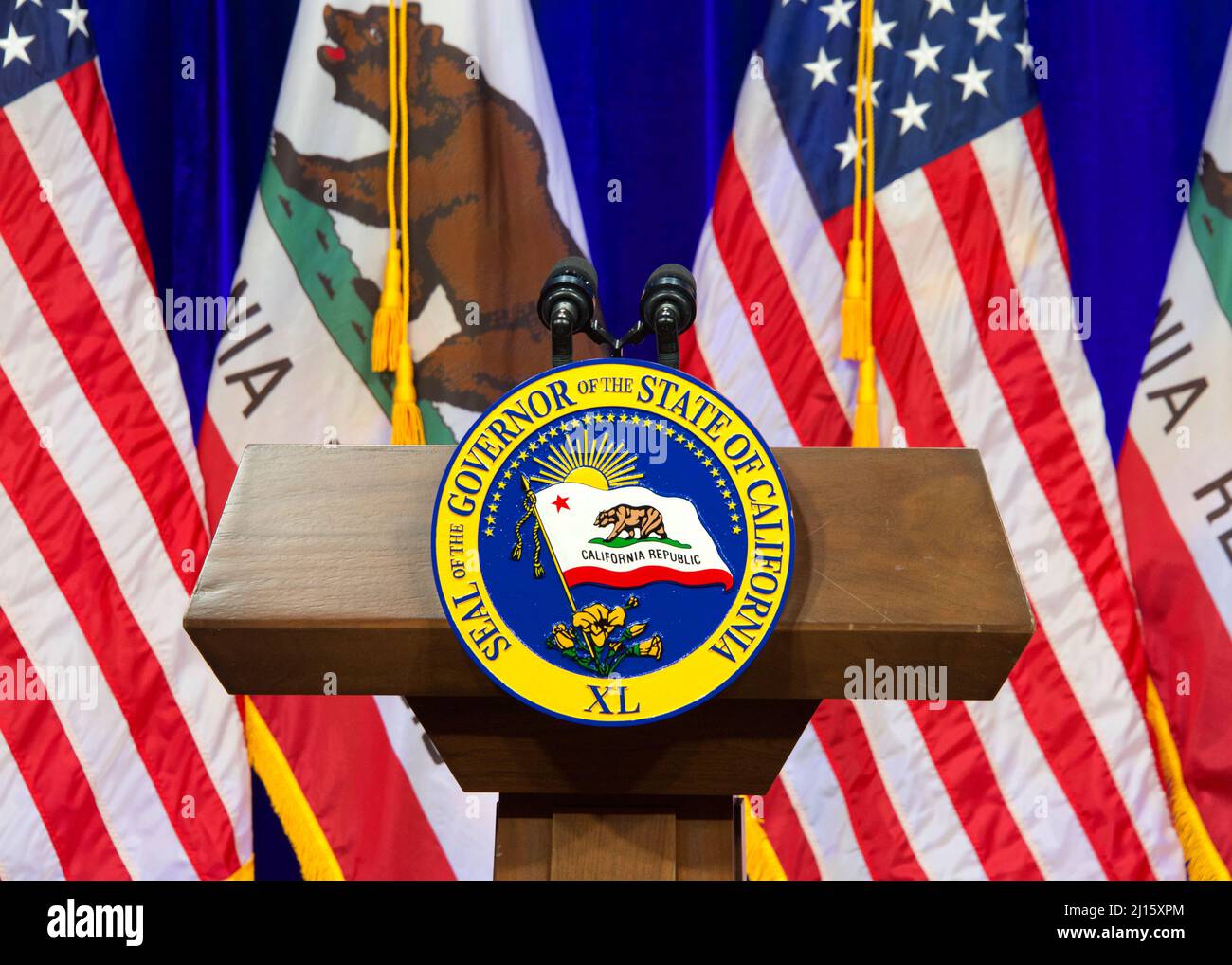 Sacramento, CA - March 8, 2022: Seal of the Governor of the State of California on a wood podium with American and California flags alternating behind Stock Photo
