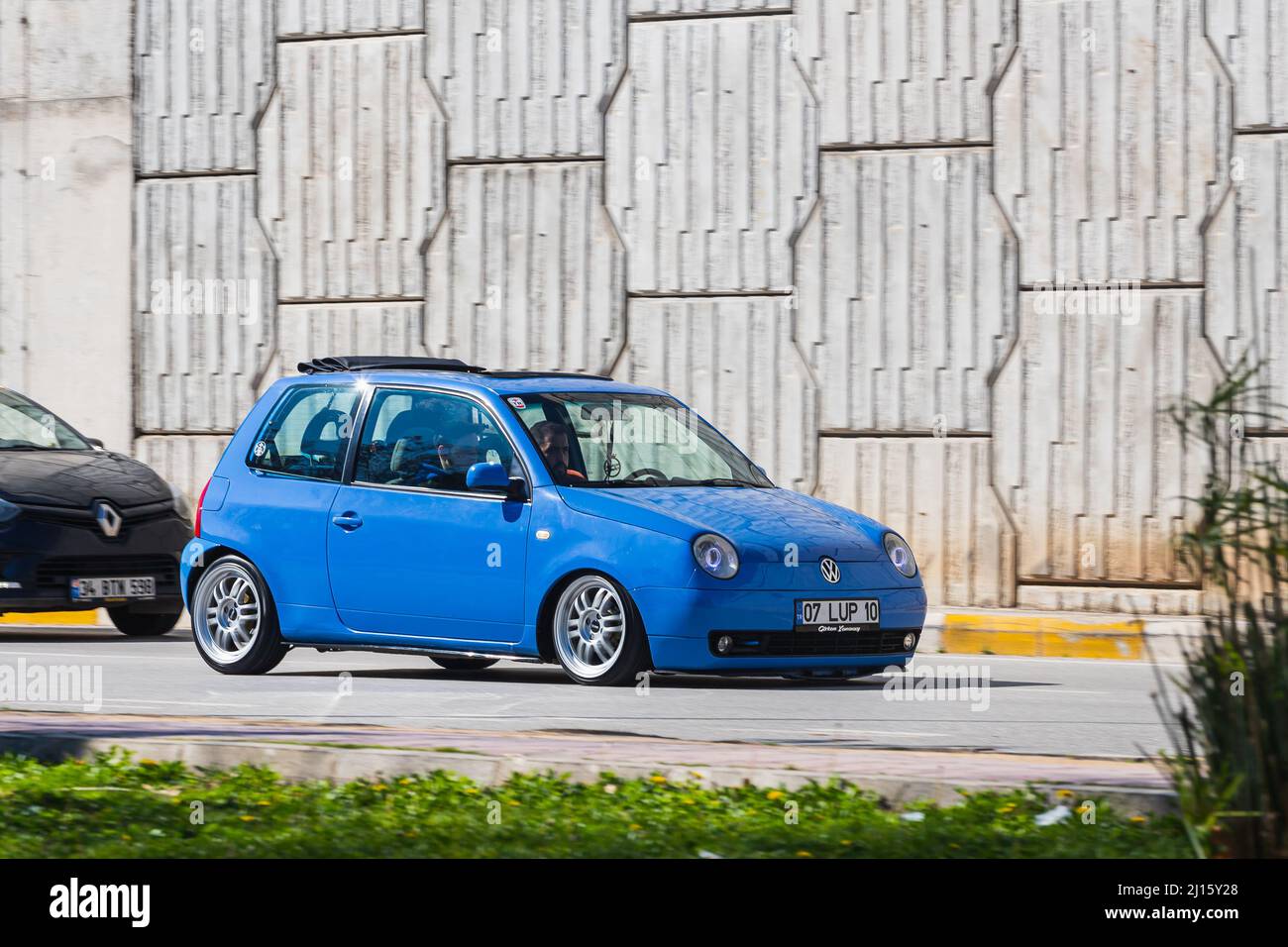 Antalya; Turkey – March 04 2022: blue Volkswagen Lupo is driving fast on the street on a warm summer day against the backdrop of a  bridge Stock Photo