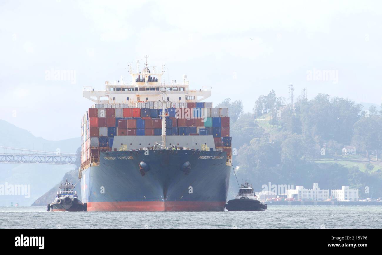 Oakland, CA - Feb 14, 2022: Tugboats assisting APL cargo ship PRESIDENT CLEVELAND maneuver into the Port of Oakland, the fifth busiest port in the Uni Stock Photo