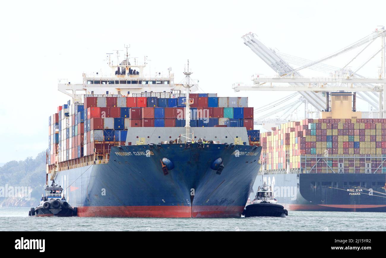 Oakland, CA - Feb 14, 2022: Multiple Tugboats assisting APL cargo ship PRESIDENT CLEVELAND to turn maneuver into the Port of Oakland. Stock Photo