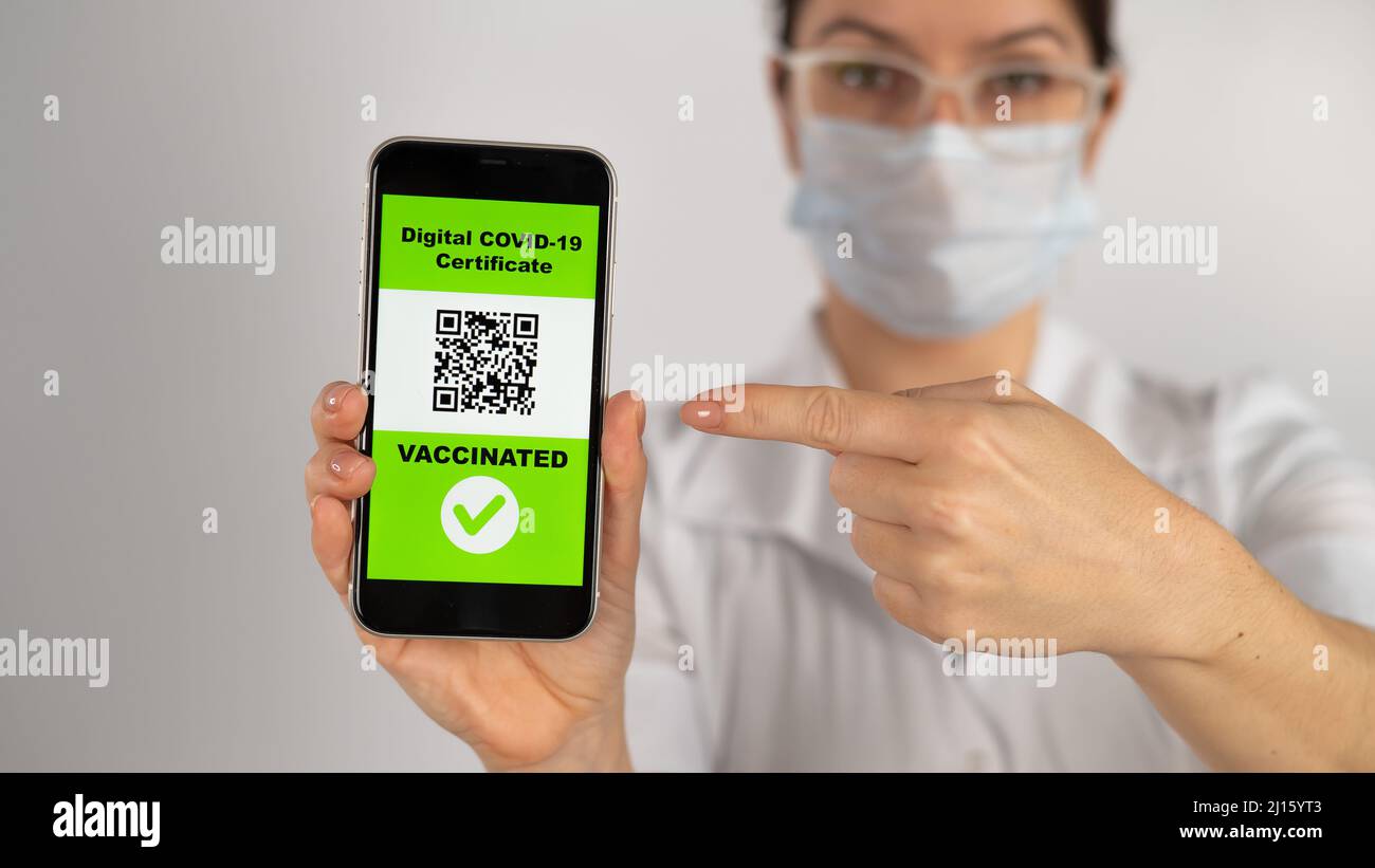 The doctor recommends vaccination and holds a smartphone with a QR code ...