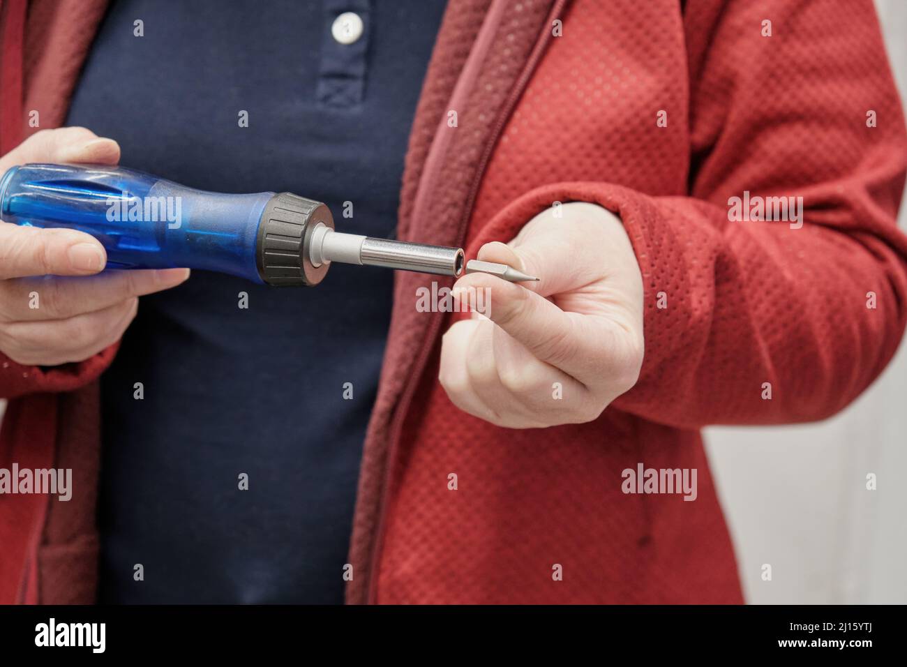 Woman in building materials store buys screwdriver with replaceable attachments Stock Photo