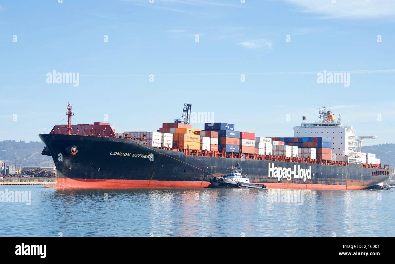 Oakland, CA - March 01, 2022: Tugboats assisting Hapag-Lloyd cargo ship LONDON EXPRESS maneuver into the Port of Oakland. Stock Photo