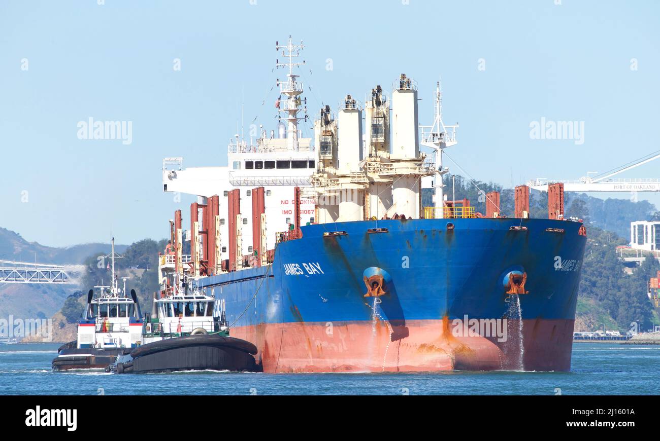 Oakland, CA - March 10, 2022: Tugboats assisting Pacific Basin Bulk Carrier JAMES BAY to maneuver into the Port of Oakland. Stock Photo