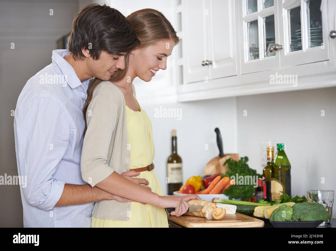 Making dinner lovingly. Shot of a young couple in their kitchen preparing dinner together. Stock Photo
