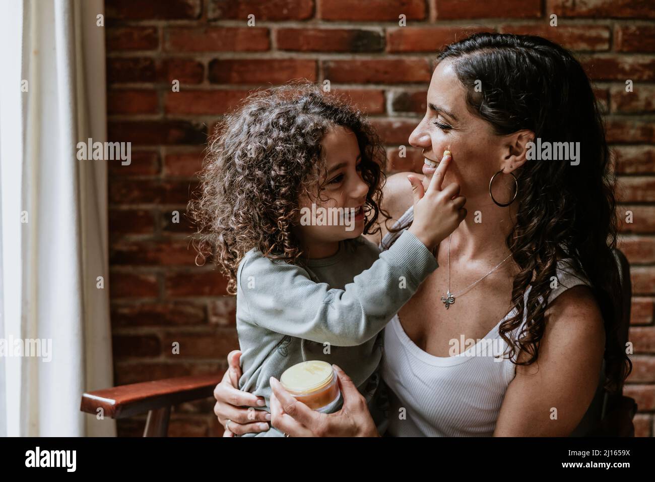 Mother and daughter putting on Facial cream or masks at home in Mexico