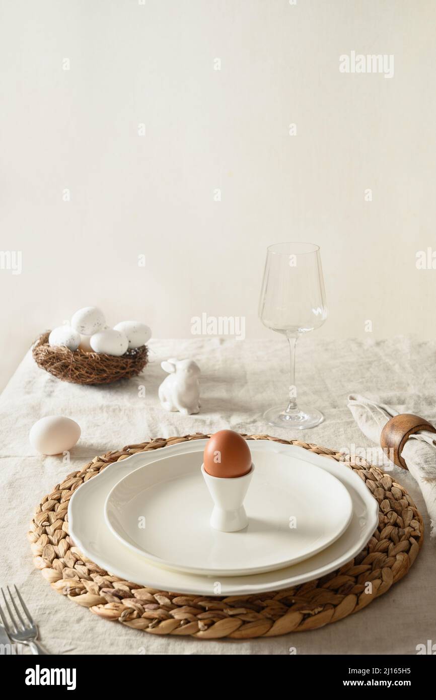 Easter festive dinner with organic egg and decorative nest on linen tablecloth. Vertical format. Close up. Stock Photo