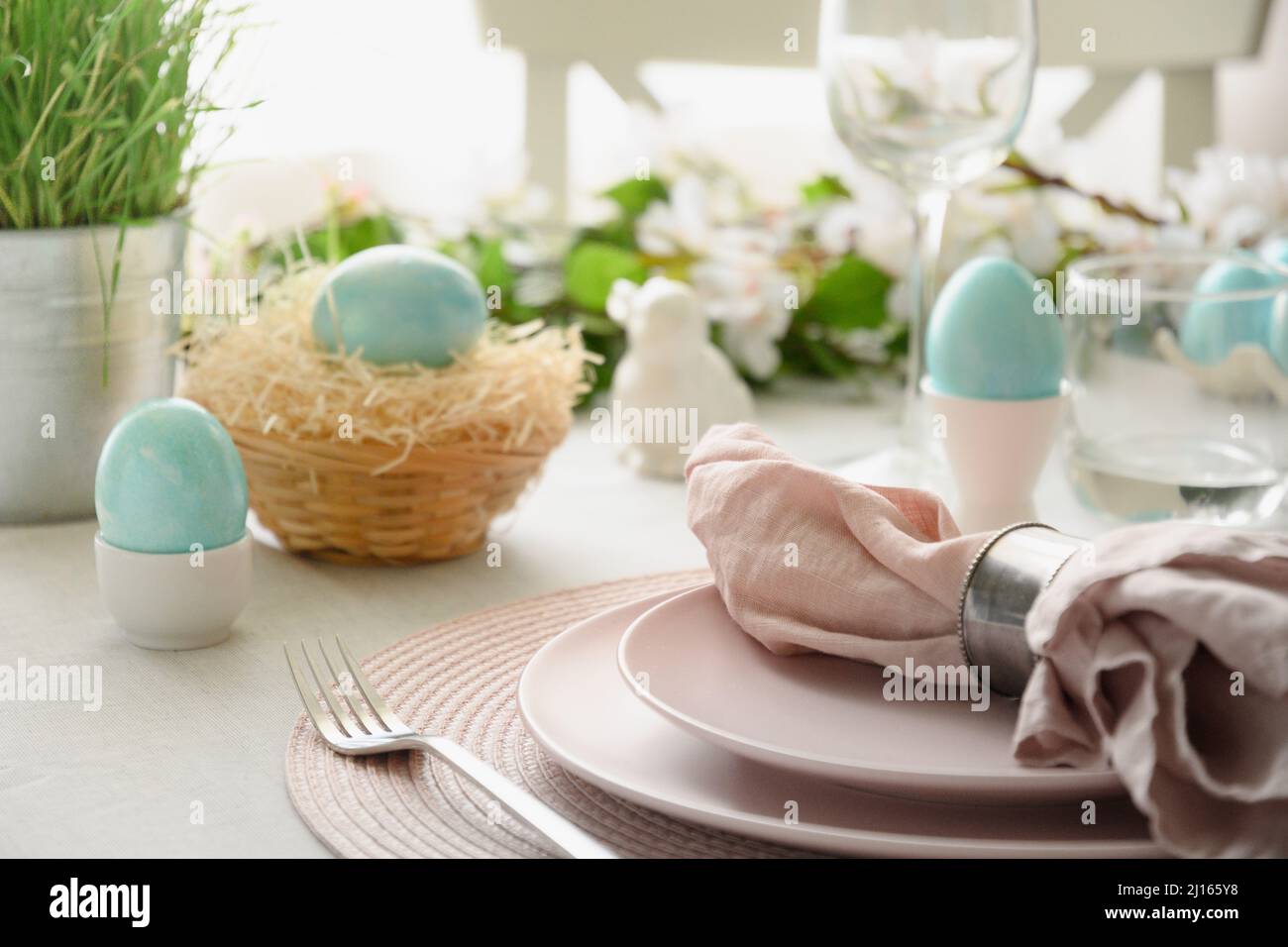 Easter table setting with blue eggs, spring decorations, fresh flowers. Elegance dinner in interior. Close up. Stock Photo