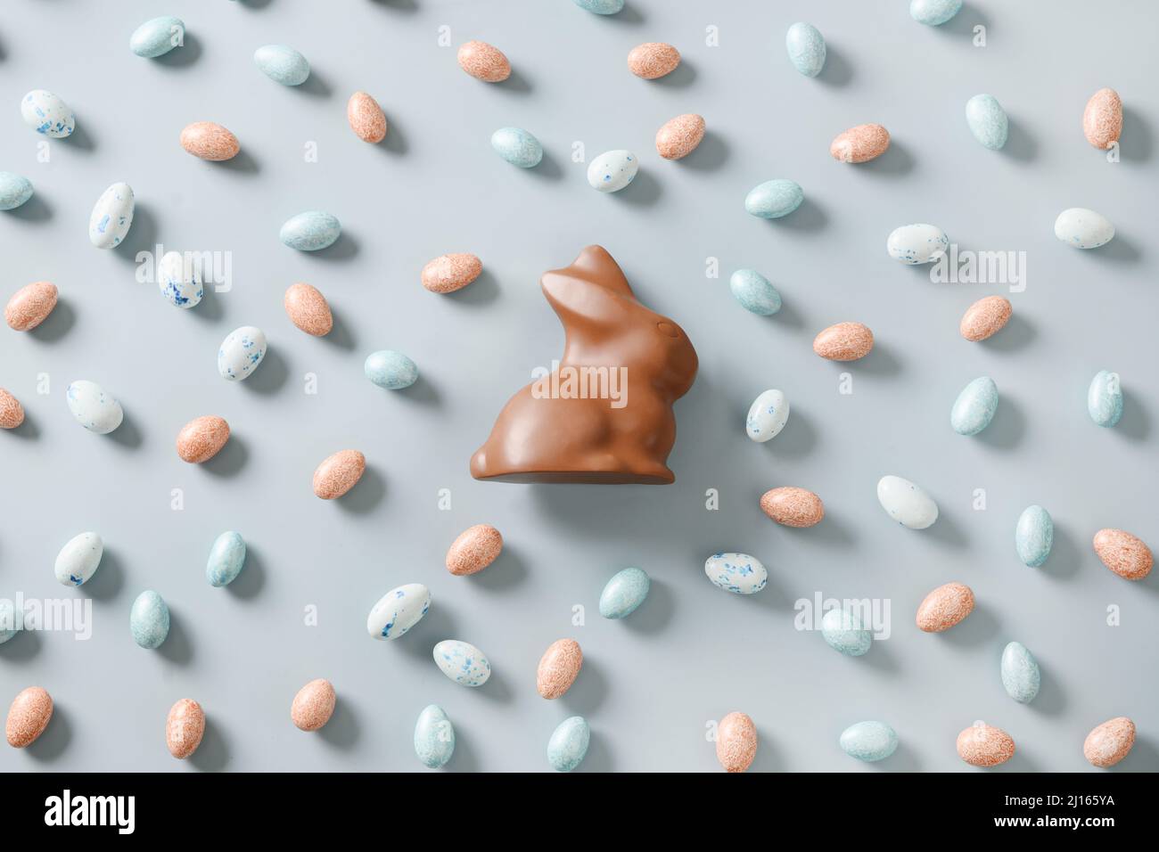 Easter chocolate eggs and rabbit on blue background. View from above. Concept Easter eggs hunt. Flat lay. Stock Photo