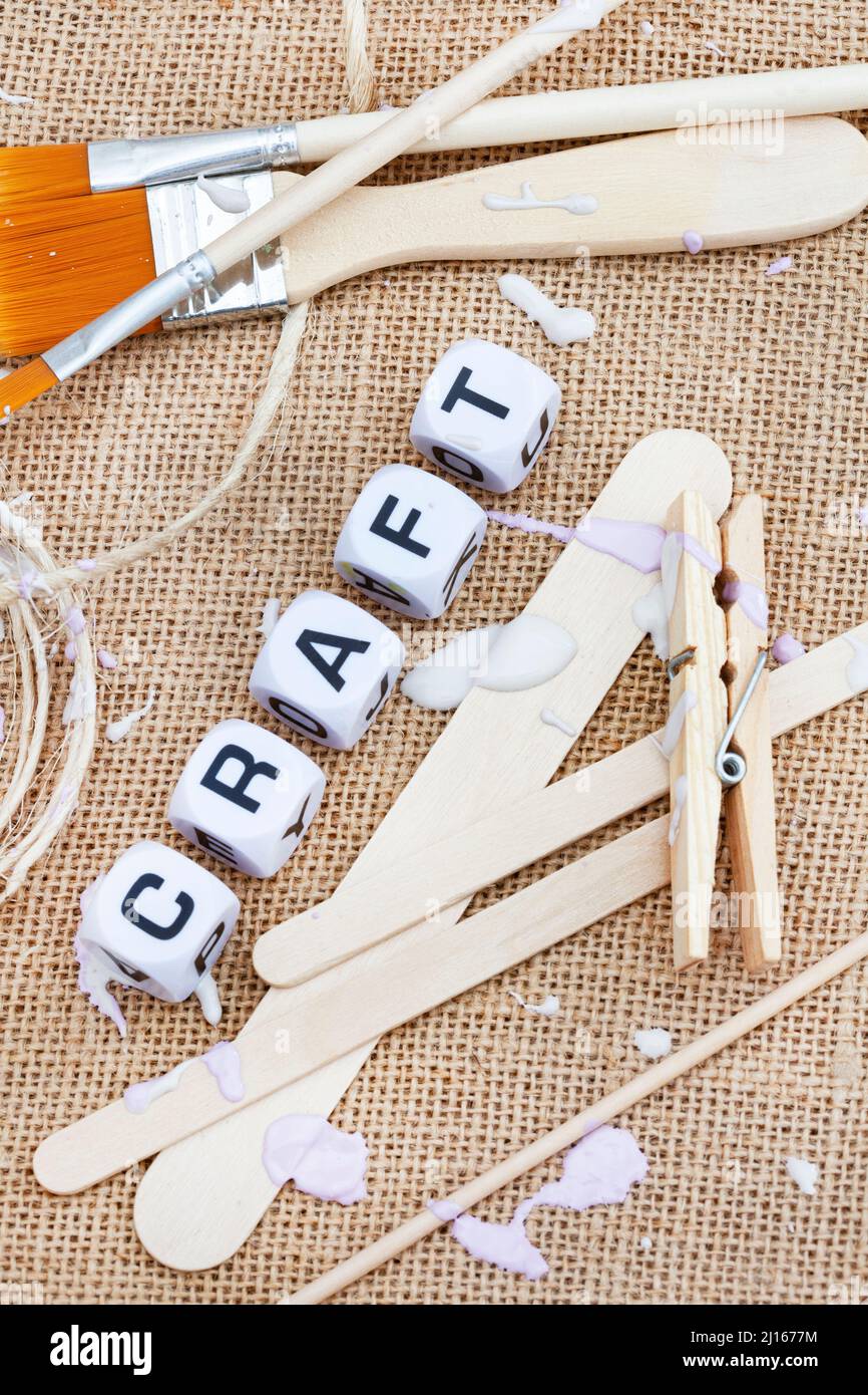 rustic hessian surface with neutral colored paint pallet, pastel colored paint splatter and the word craft in letter dice and ample copy space Stock Photo