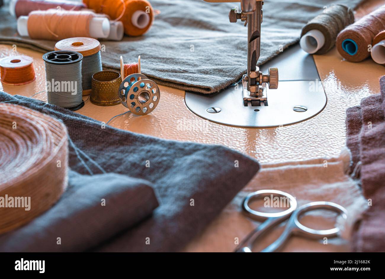 Sewing machine, thread, scissors and fabric close-up. The tailor's workplace. Side view, horizontal. Stock Photo