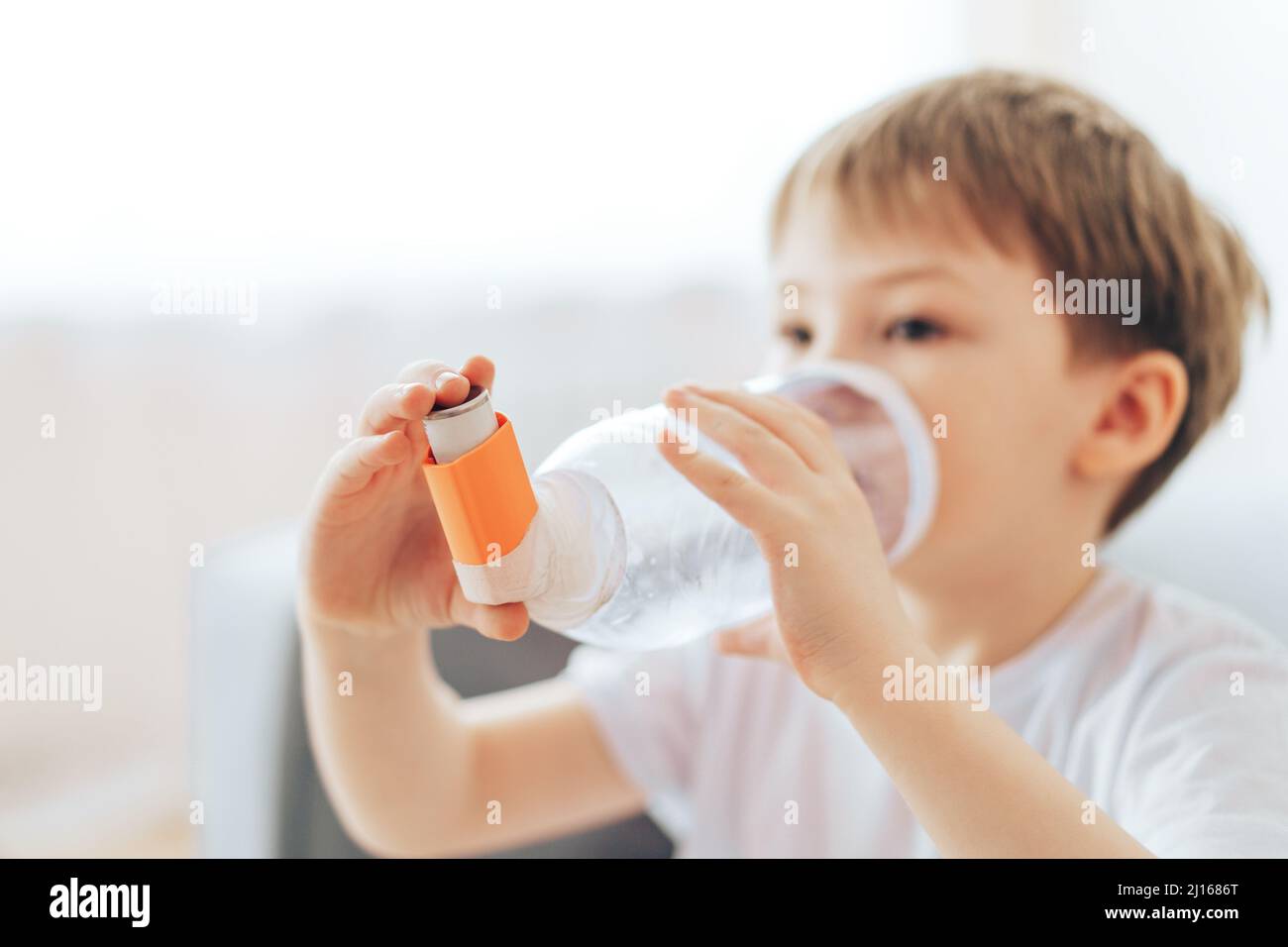 Boy inhales asthma medicine through homemade spacer Stock Photo