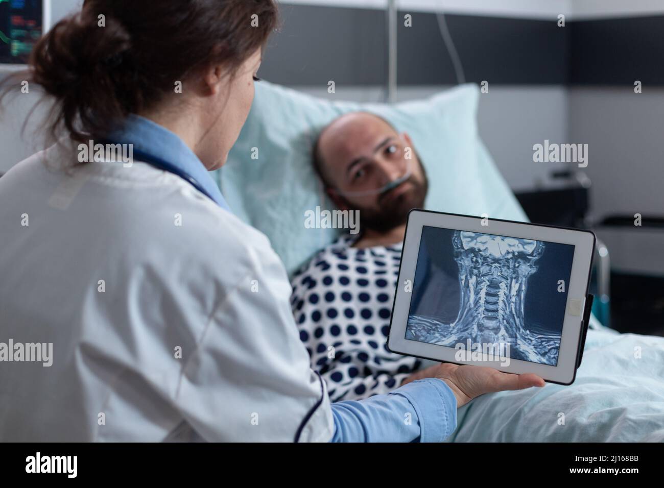 Medical doctor presenting options to patient for treating throat affliction while looking at mri scan on digital tablet. Middle aged man with cervical issues having low oxygen saturation. Stock Photo