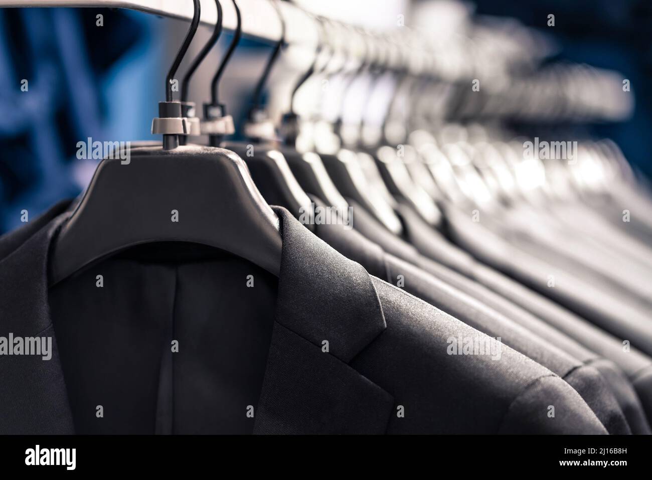 Suits in fashion store for men or in hanger in wardrobe. Jacket rack in apparel retail shop. New elegant luxury collection. Stock Photo