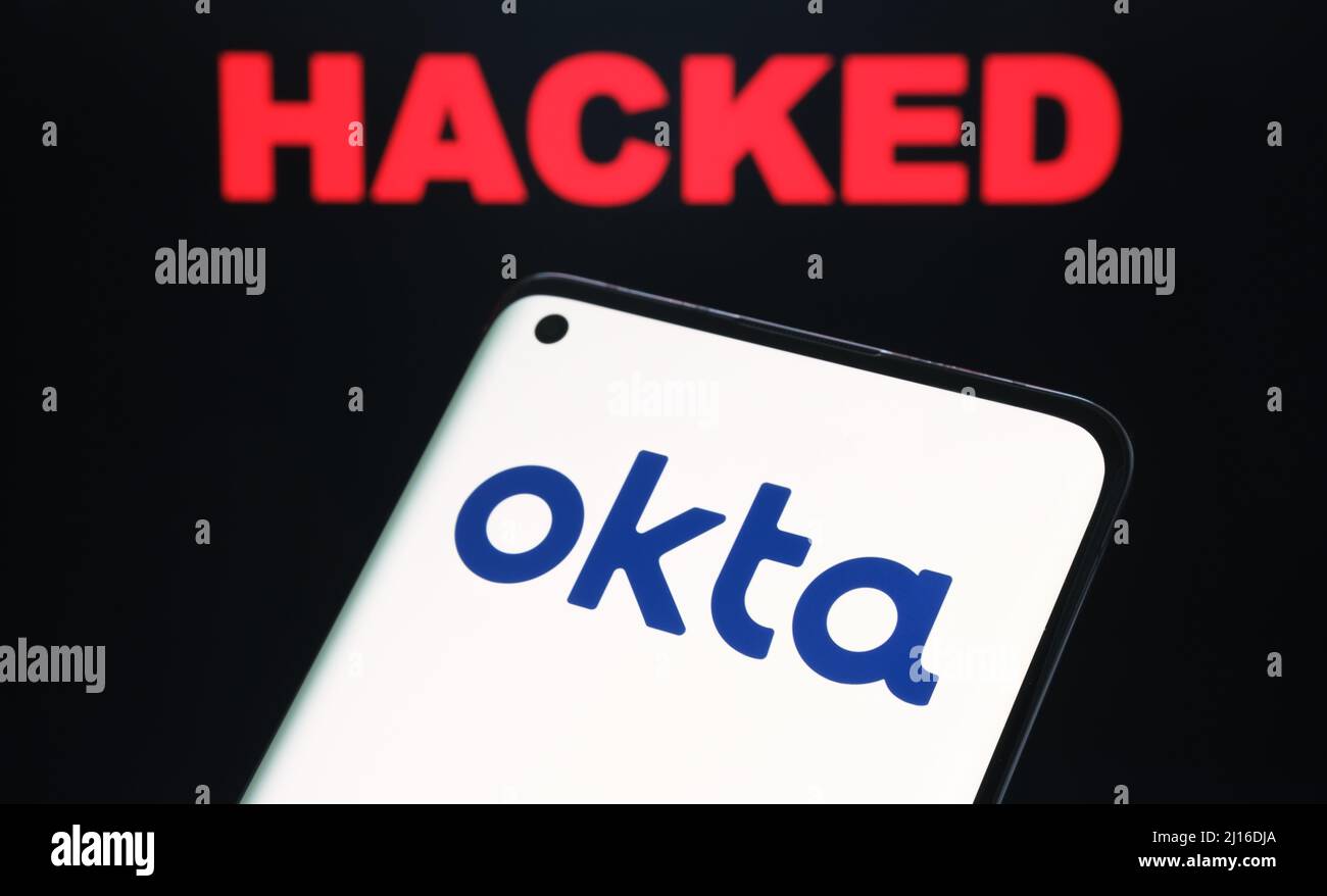 Okta security firm logo seen on smartphone and the word HACKED on blurred background. Concept for hack. Stafford, United Kingdom, March 22, 2022. Stock Photo