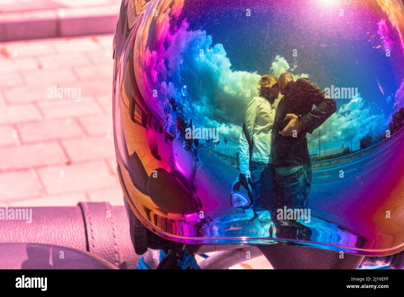 A man stands next to a woman in the reflection of a bubble visor helmet. Mirror visor Stock Photo