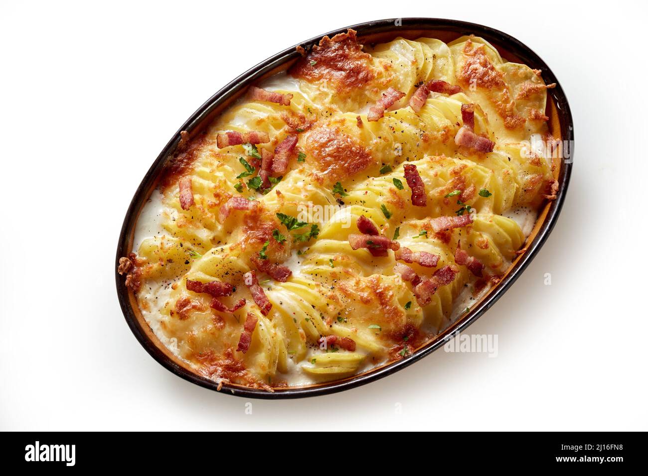 Top view of appetizing gratin with baked sliced potato and crispy bacon pieces baked in oval shaped pan placed on white background Stock Photo