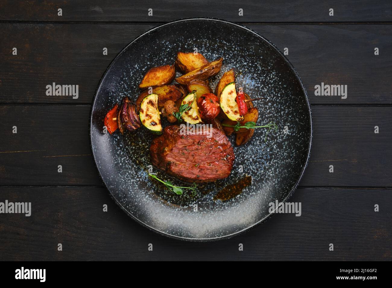 Top view of juicy beef steak with potato wedges and grilled vegetables on skewer Stock Photo