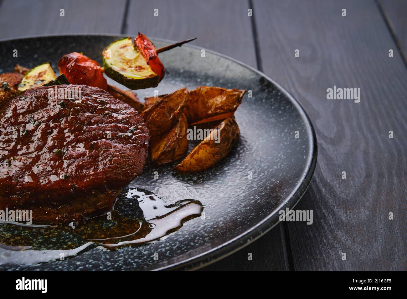 Closeup view of juicy beef steak with potato wedges and grilled vegetables on skewer Stock Photo