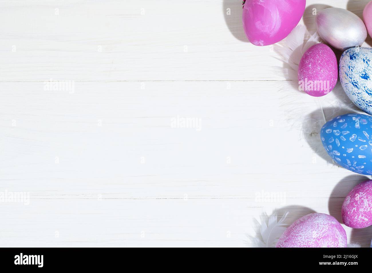 Collection of Easter eggs. Chicken eggs painted blue and pink lie on a white wooden background. Creative greeting card with Easter. Frame. Top view. C Stock Photo