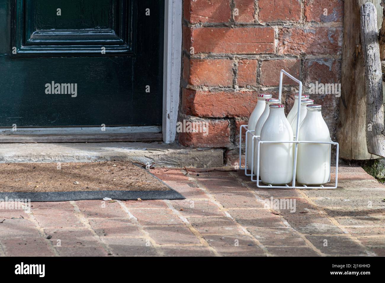 Six bottles of milk (pints of milk) delivered by a milkman and left in a crate on the doorstep of a house, UK Stock Photo