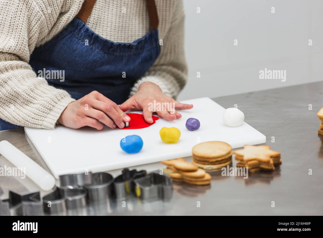 Crop baker cutting colorful gum paste in bakery Stock Photo